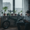 Młody mężczyzna w mieszkaniu przegląda tablet przy składanym fatbike’u ENGWE zaparkowanym obok biurka – e-bike w codziennym życiu miejskim